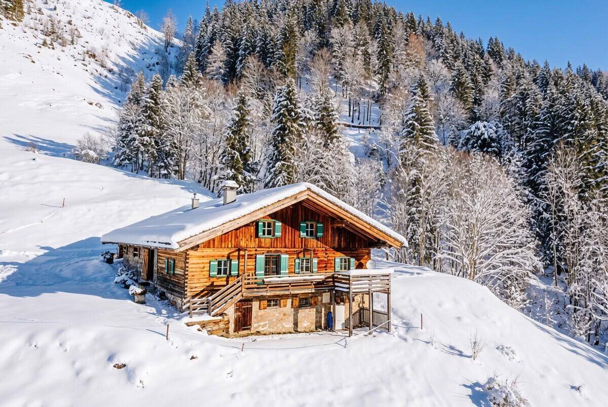 Charmantes Chalet im Winter mit schneebedeckten Dächern und umgebenden Wäldern.