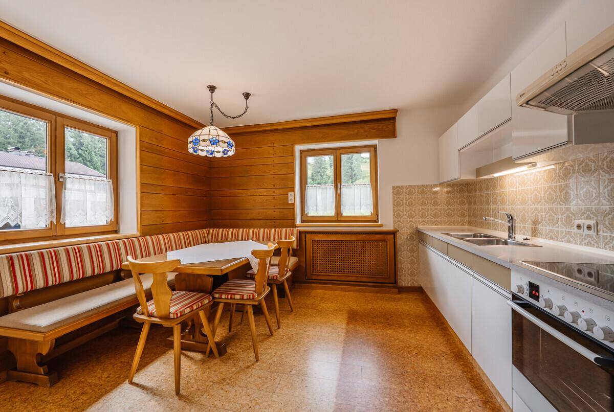 Helle Küche mit Essbereich, weißen Schränken und traditionellen Holzakzenten, funktional und einladend.
