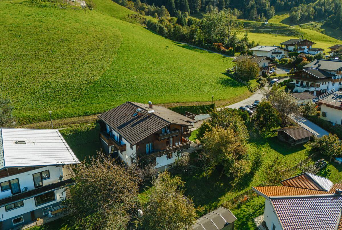 Luftaufnahme des Hauses mit traditioneller Architektur, umgeben von einem gepflegten Garten und grünen Hügeln.