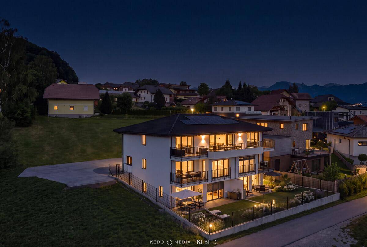 Moderne Wohnanlage bei Nacht mit beleuchteten Balkonen und umliegender Wohnbebauung.