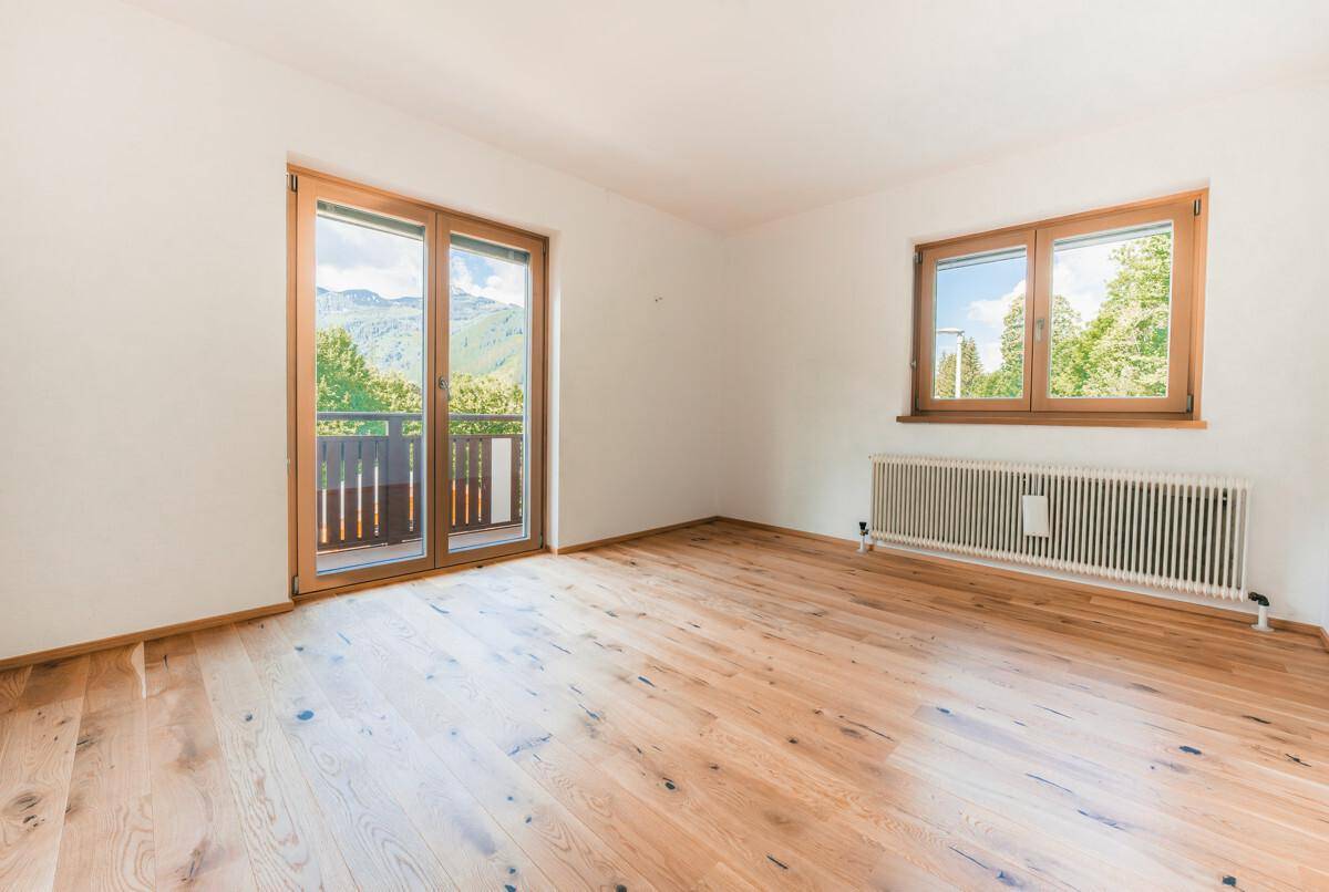 Helles Zimmer mit Holzboden und Zugang zu einem Balkon, bietet einen schönen Ausblick.