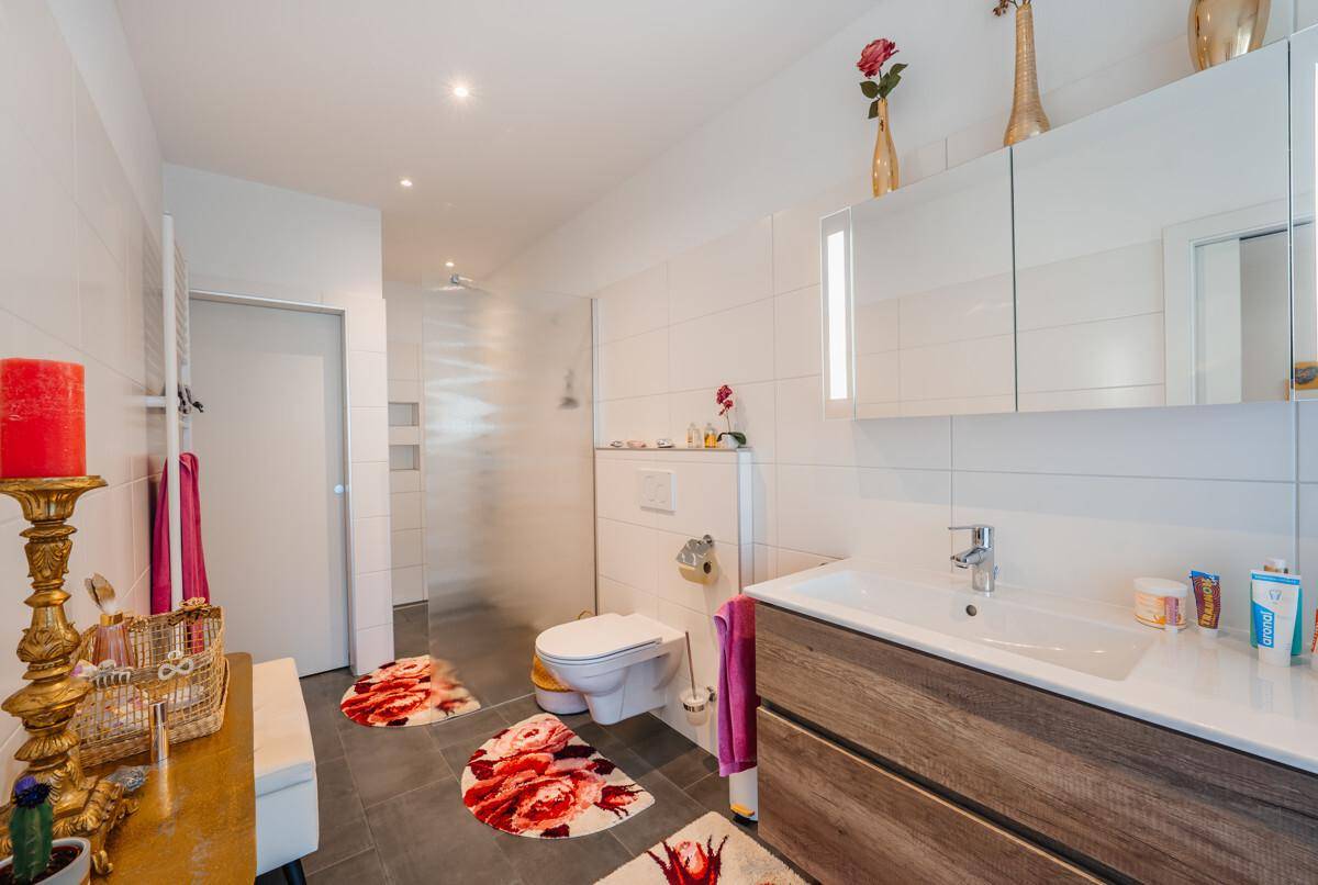 Modernes Badezimmer mit Waschtisch, wandhängendem WC und einer geräumigen begehbaren Dusche.