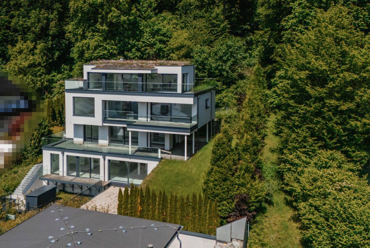 Moderne Architektur mit mehreren Terrassen und Gründach, eingebettet in eine grüne Hanglage.