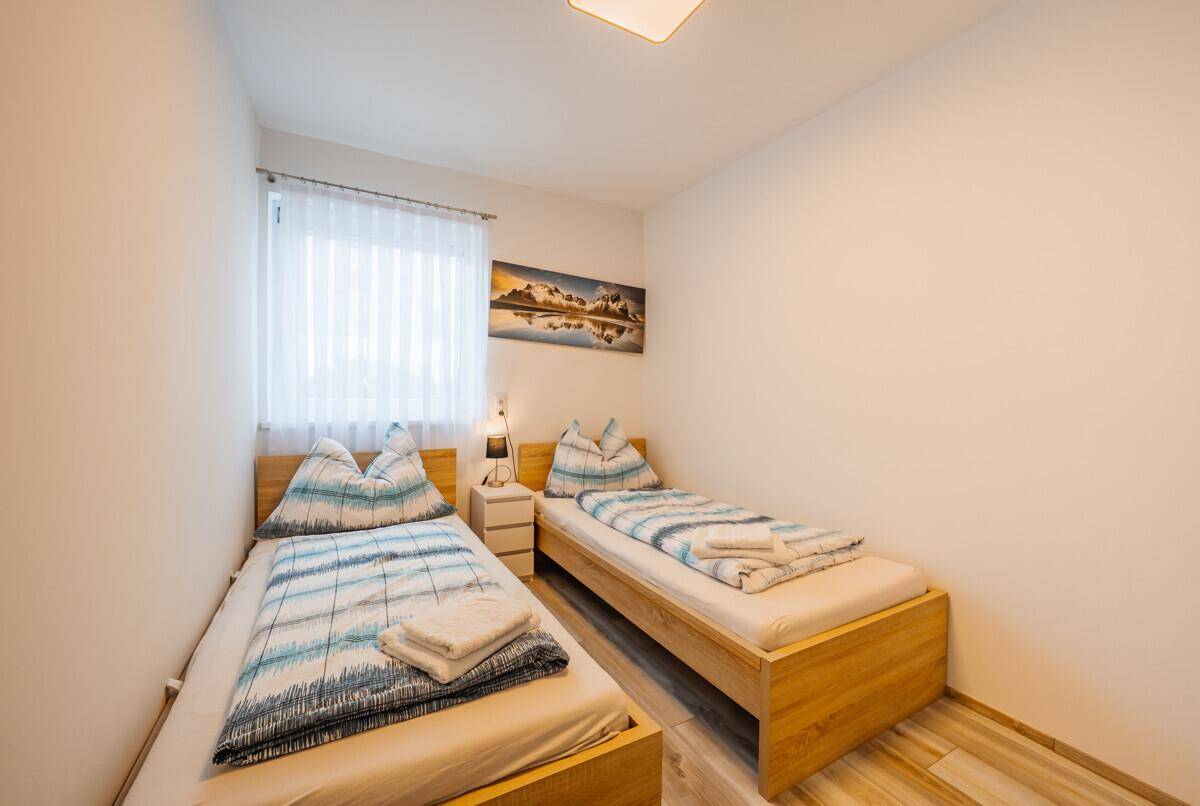 Helles Schlafzimmer mit zwei Einzelbetten und Fenster.