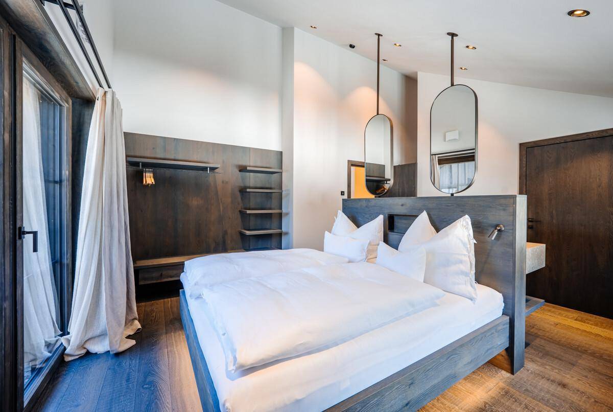Helles Schlafzimmer mit Holzboden, hohen Decken und offenem Kleiderschrankbereich.