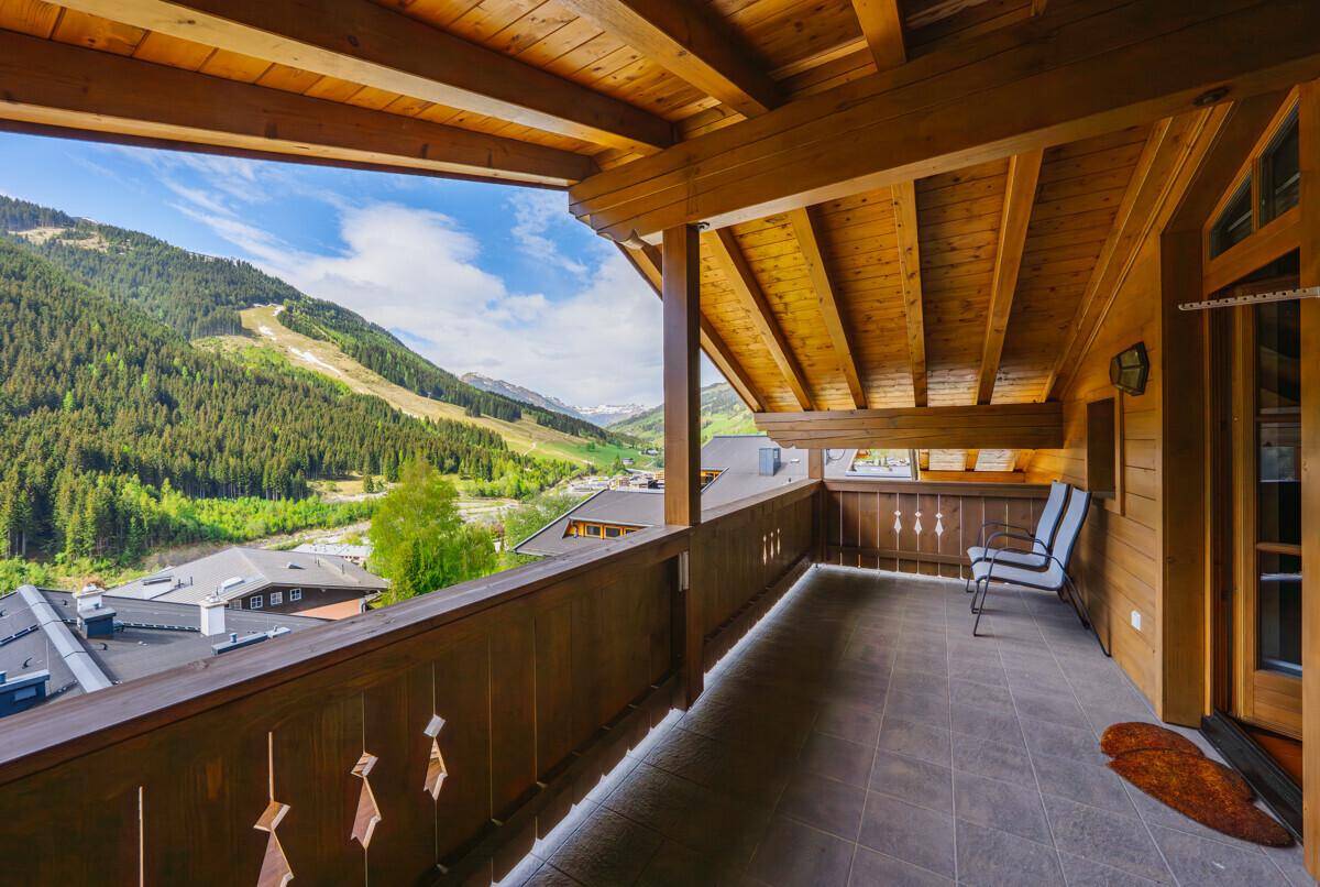 Großer Holzbalkon mit weitem Blick über das Tal und die umliegenden Berge.