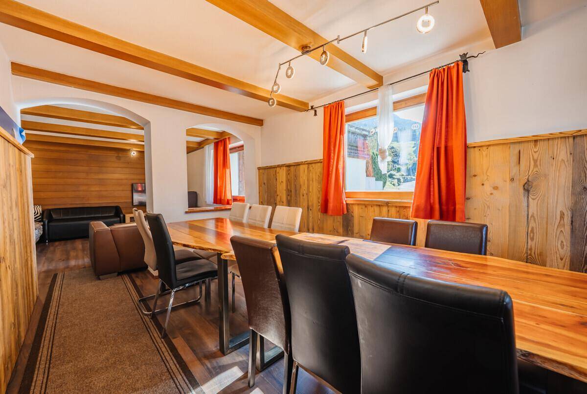 Geräumiger Essbereich mit langem Holztisch, sichtbaren Deckenbalken und traditioneller Holzvertäfelung.