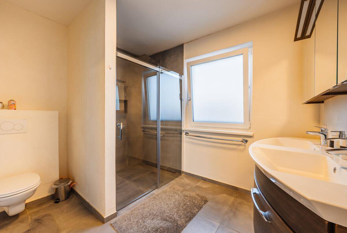 Funktionales Badezimmer mit Duschkabine, WC und Fenster.