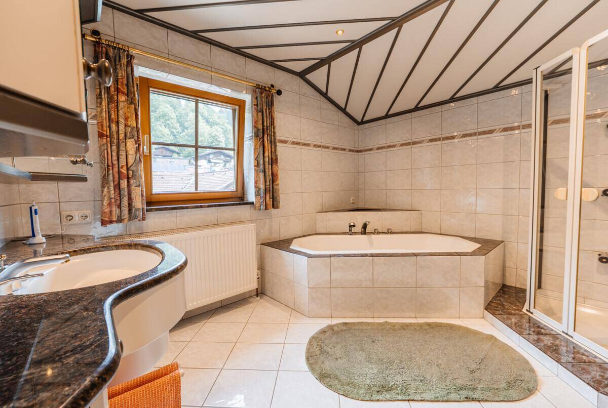 Geräumiges Badezimmer mit Eckbadewanne, separater Dusche und Fenster, hell gefliest.