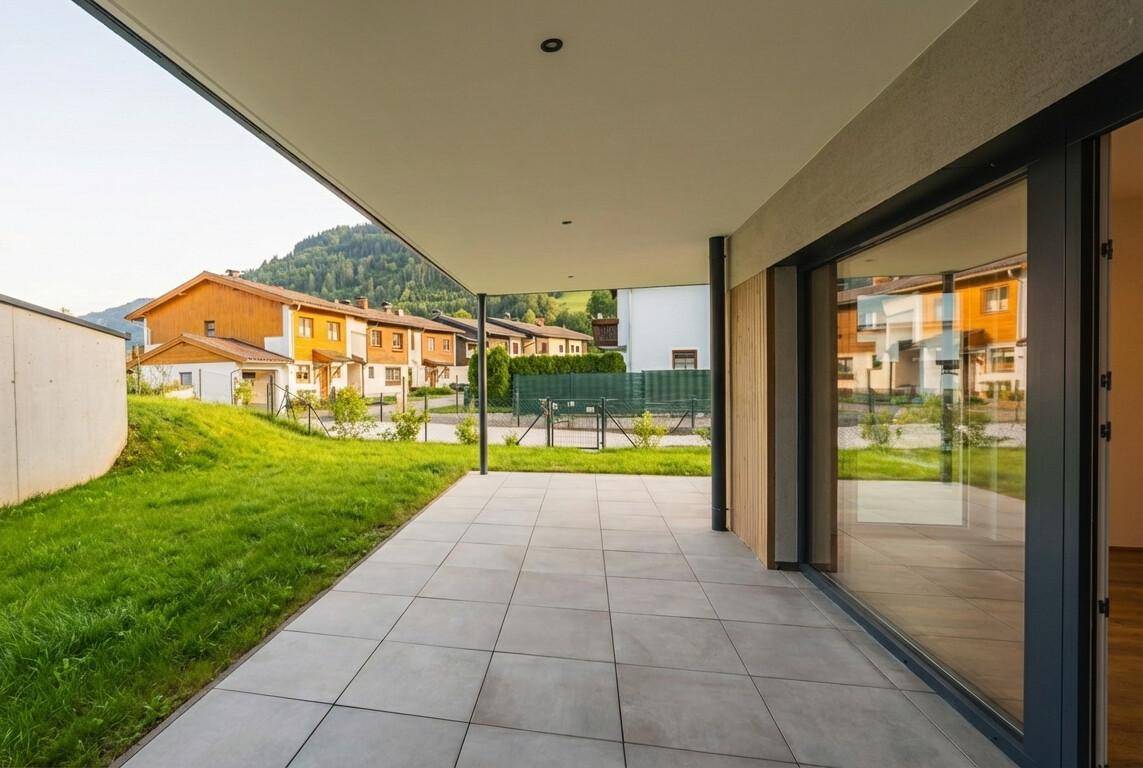 Große, geflieste Terrasse mit Blick auf die umliegende Berglandschaft und grüne Wiesen.
