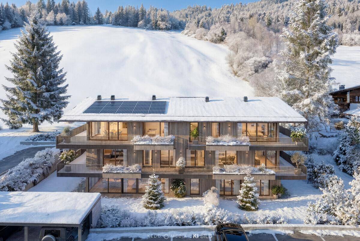 Modernes Gebäude mit Holzfassade, Balkonen und Solaranlage, eingebettet in eine verschneite Winterlandschaft.