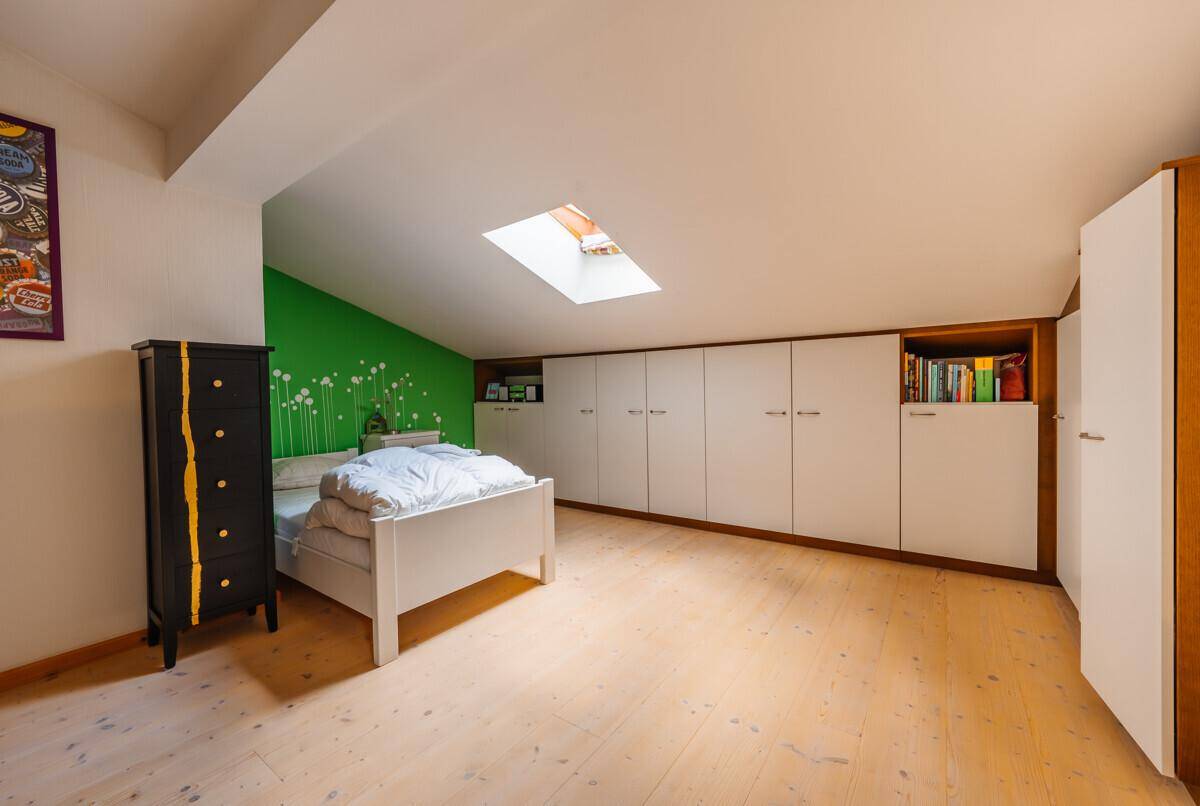Kinderzimmer mit Dachschräge, Einbauschränken und einem Oberlicht für natürliches Licht.