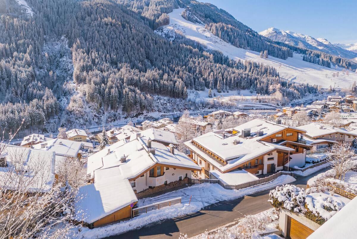 Winterlandschaft eines Bergdorfes mit schneebedeckten Dächern und verschneiten Bäumen.