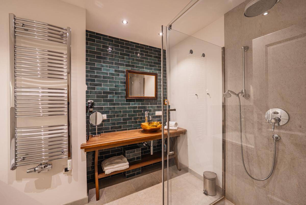 Modernes Badezimmer mit begehbarer Dusche, Holzwaschtisch und beheiztem Handtuchhalter.