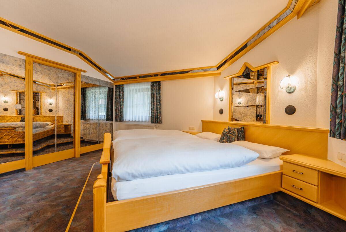 Schlafzimmer mit Doppelbett, verspiegelten Akzenten und Teppichboden, bietet eine einzigartige Atmosphäre.