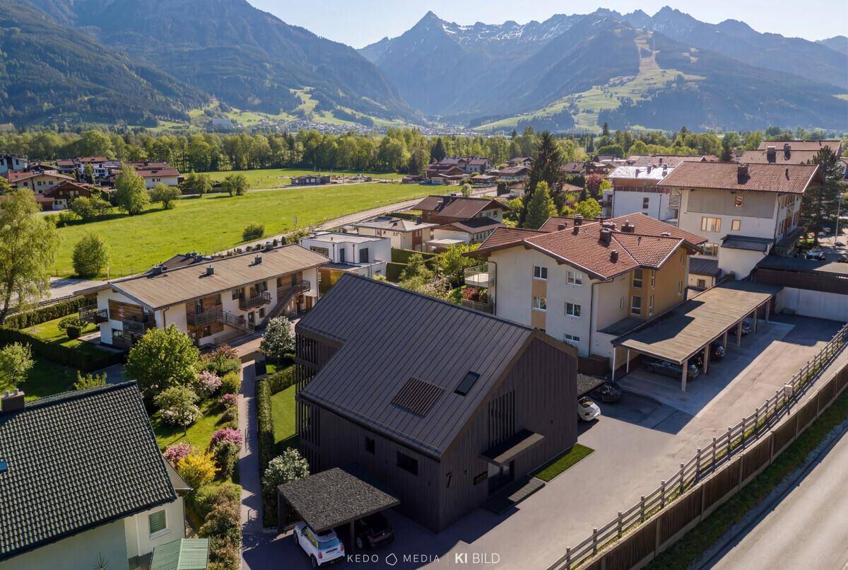 Moderne Wohnanlage in alpiner Landschaft mit Bergblick und umliegenden Häusern.