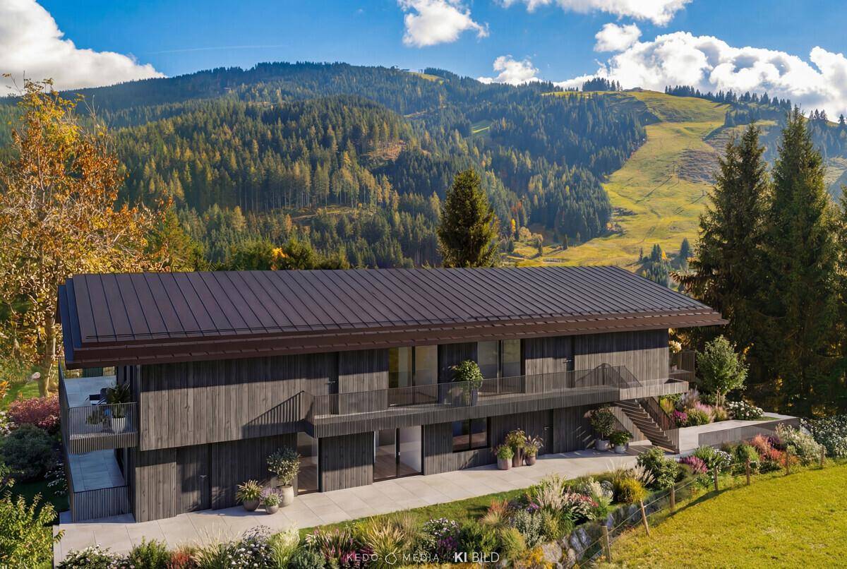 Moderne Holzfassade des Gebäudes mit Balkonen und Treppen, umgeben von alpiner Landschaft und Skipisten.