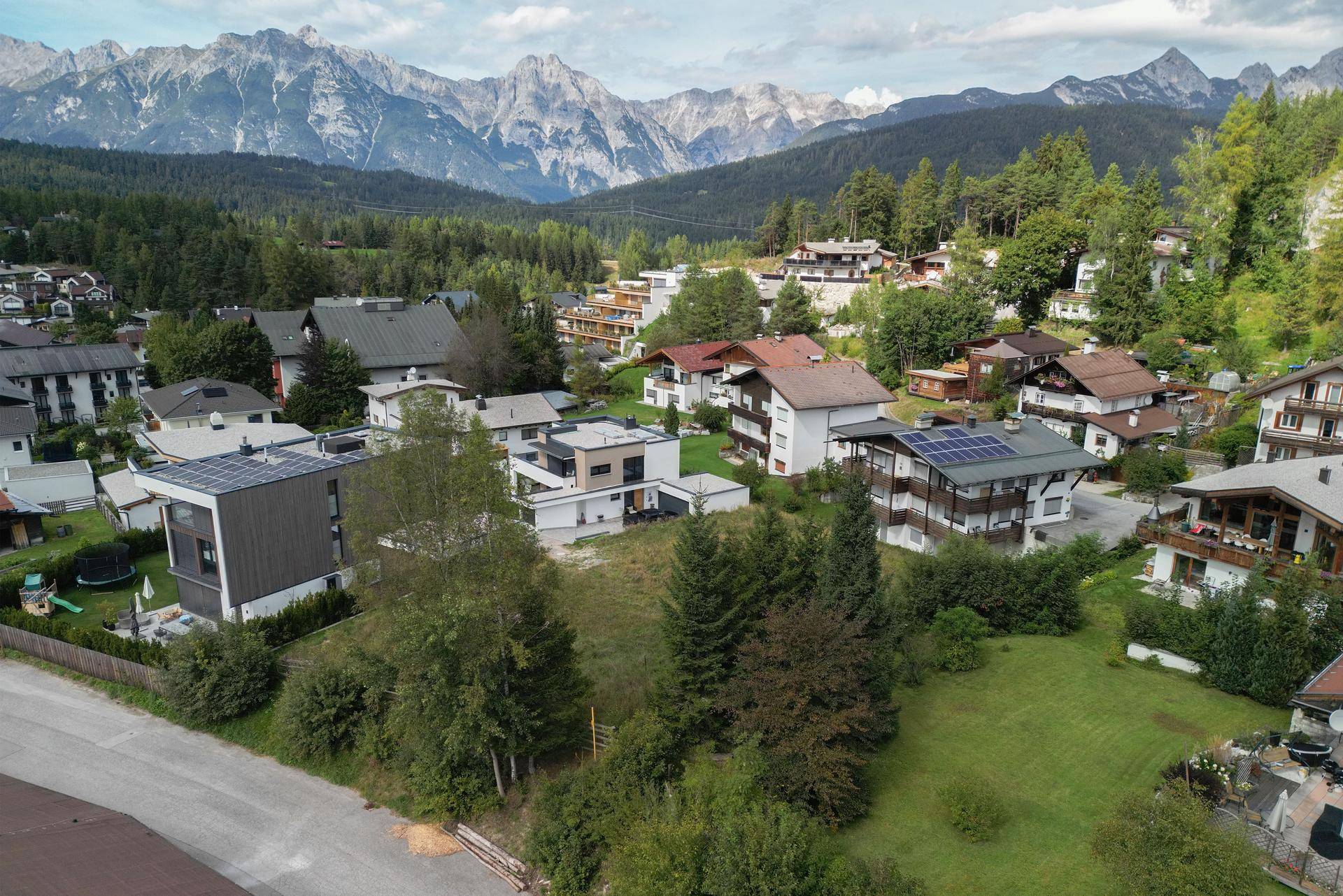 Panoramablick auf die Wohngegend mit Häusern, viel Grün und majestätischer Bergkulisse.