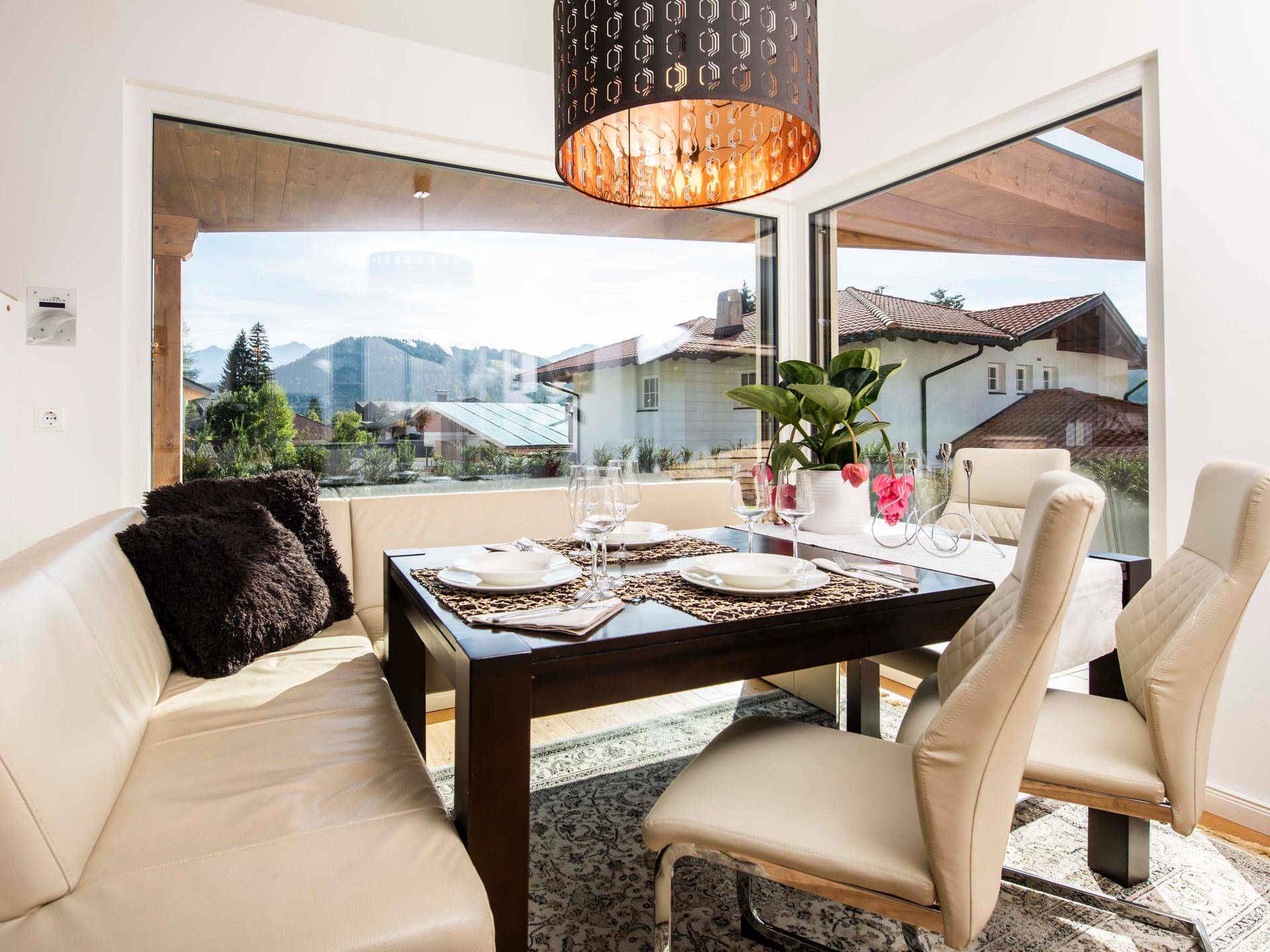 Heller Essbereich mit großen Fenstern, bequemer Sitzbank und Blick auf die umliegende Landschaft.