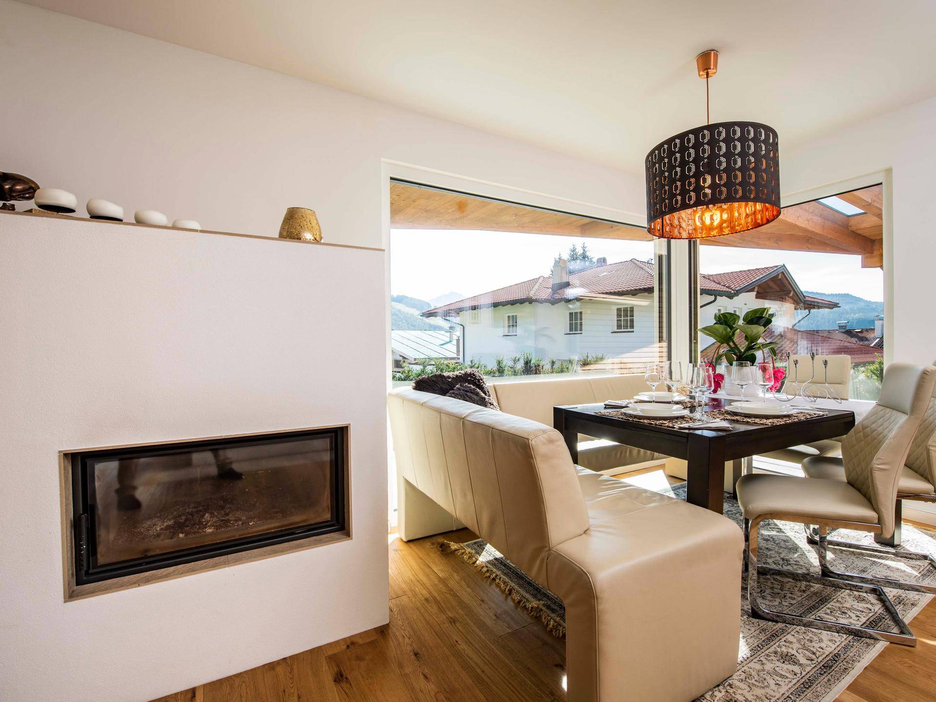 Gemütlicher Essbereich mit integriertem Kamin, Holzboden und großen Fenstern mit Aussicht.