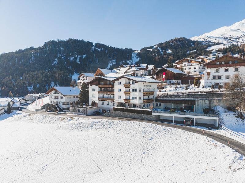 Gebäudekomplex im alpinen Stil eingebettet in eine weite, verschneite Berglandschaft.