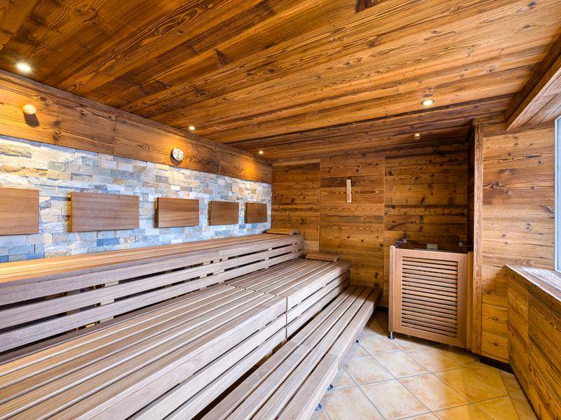 Geräumige Holzsauna mit Steinwandakzenten und mehreren Sitzebenen für Entspannung.
