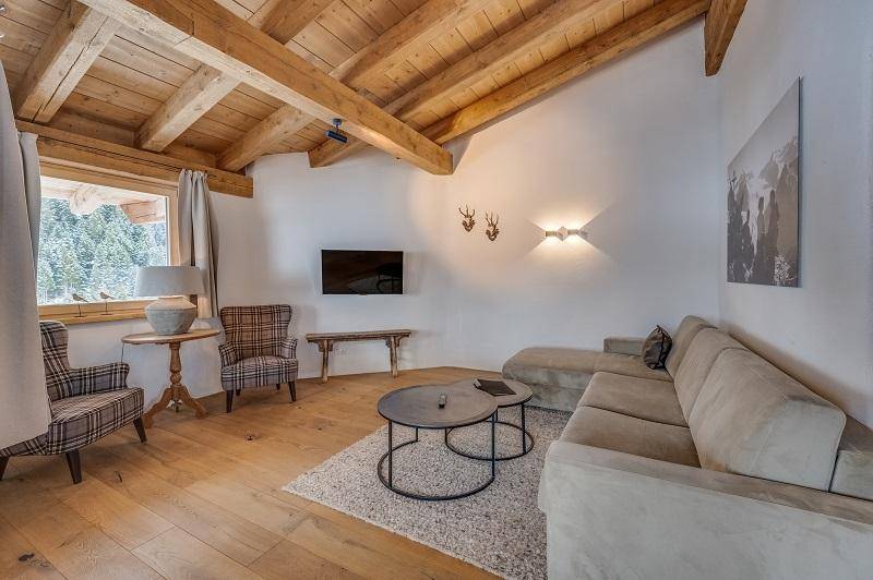 Helles Wohnzimmer mit Holzbalkendecke, beigem Sofa und traditionellen Hirschgeweih-Dekorationen.