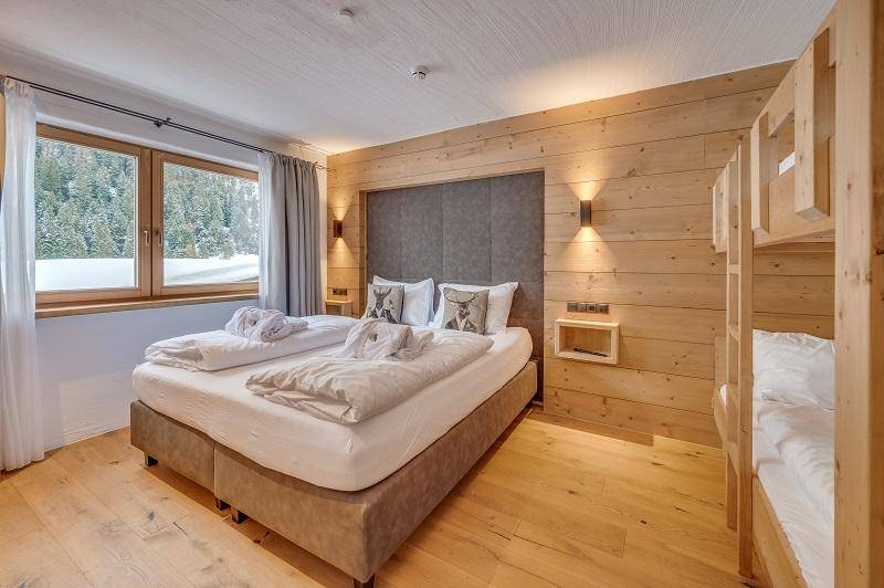 Geräumiges Schlafzimmer mit Holzwänden, Doppelbett und Etagenbett, ideal für Familien.