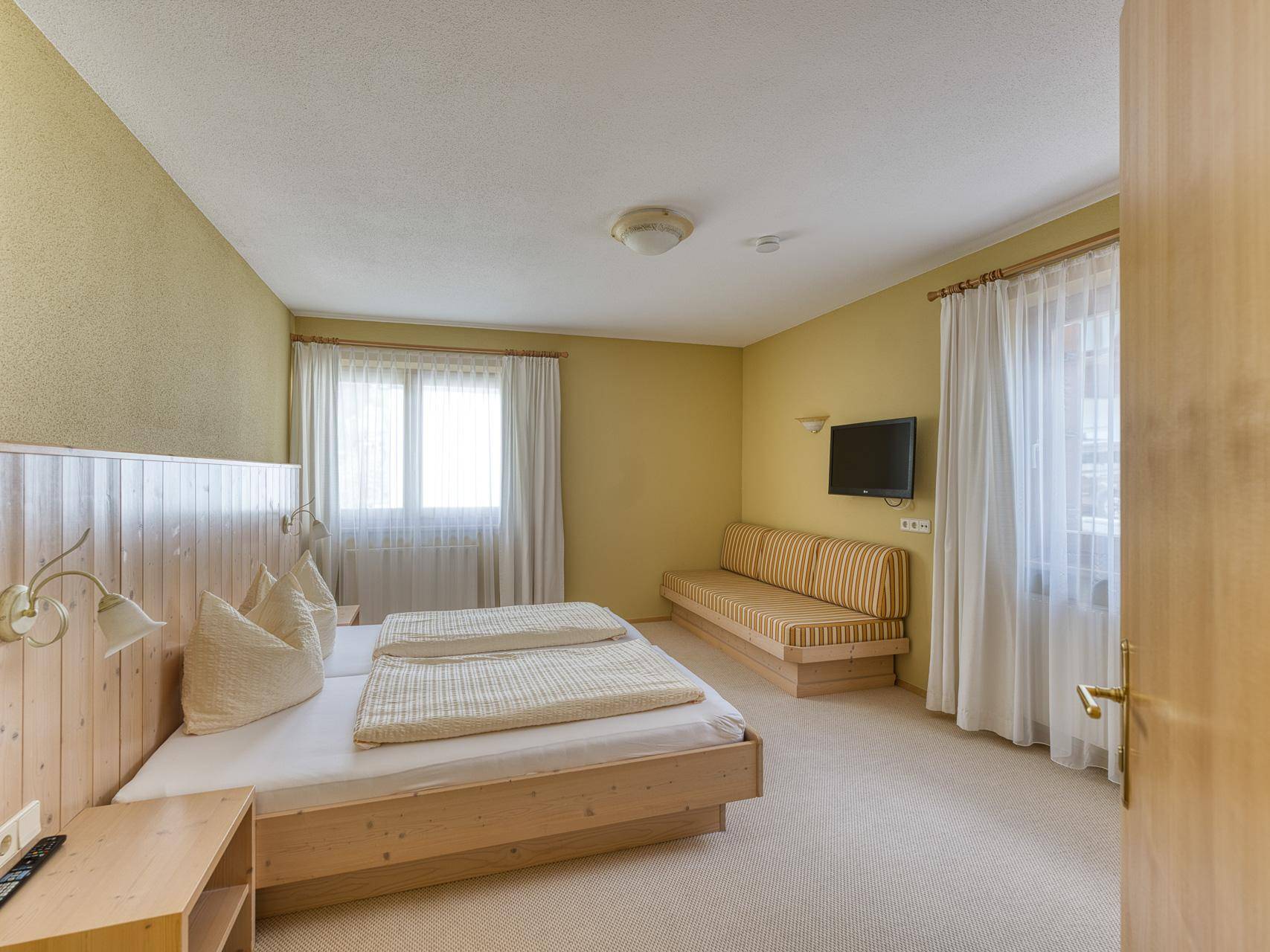 Schlafzimmer mit Doppelbett, Teppichboden und hellgelben Wänden, bietet eine gemütliche Atmosphäre.