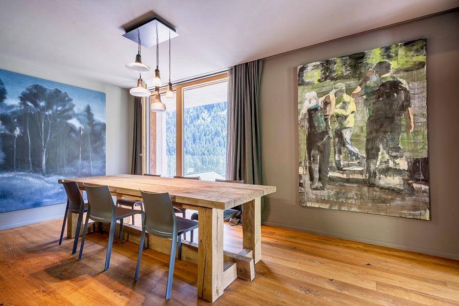 Geräumiger Essbereich mit rustikalem Holztisch, modernen Stühlen und beeindruckenden Kunstwerken.