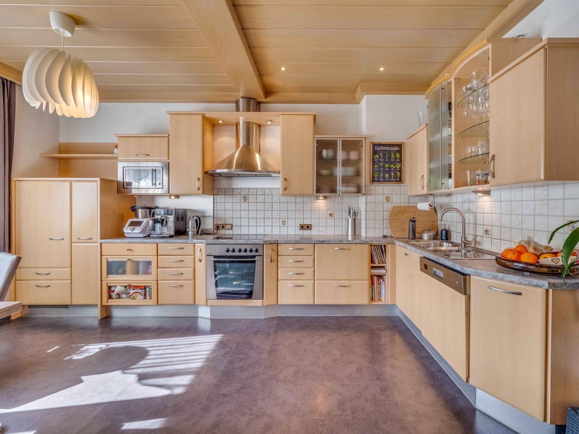 Geräumige Holzküche mit Einbaugeräten, Fliesenrückwand und Deckenbalken.