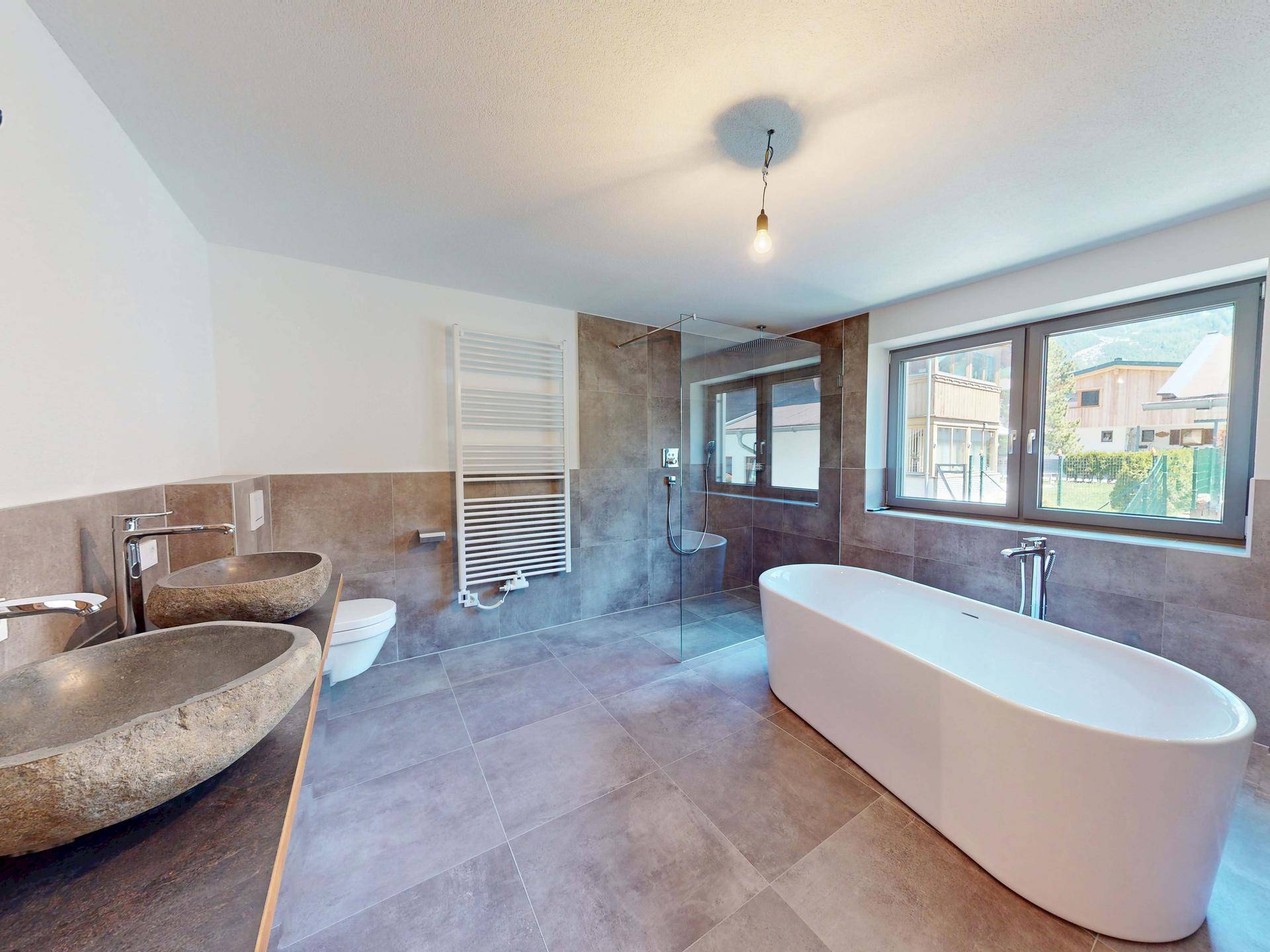 Modernes Badezimmer mit freistehender Badewanne, doppelten Steinwaschbecken und großer Dusche.