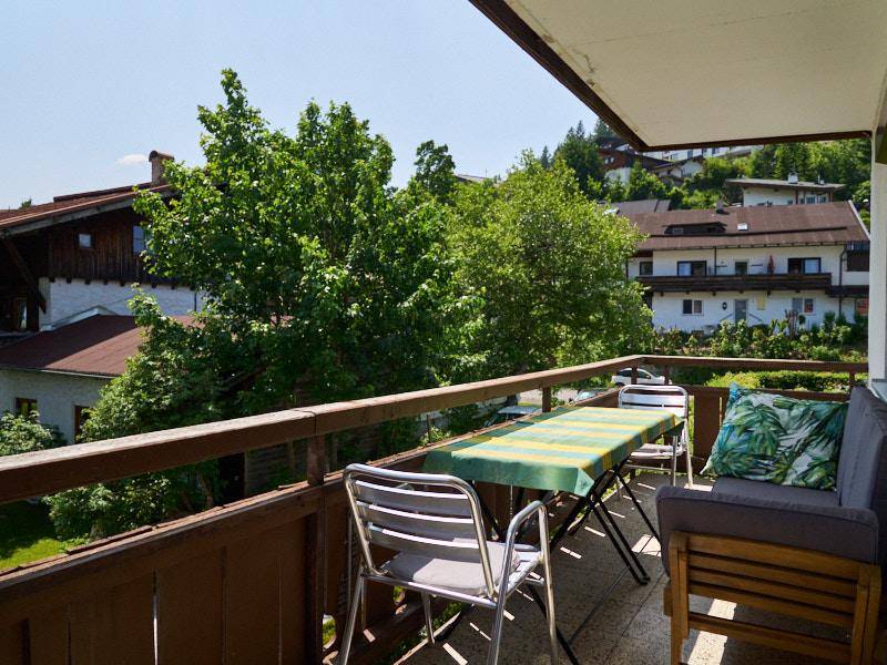 Gemütlicher Balkon mit Sitzgelegenheiten und Blick auf die umliegenden Häuser und Bäume.