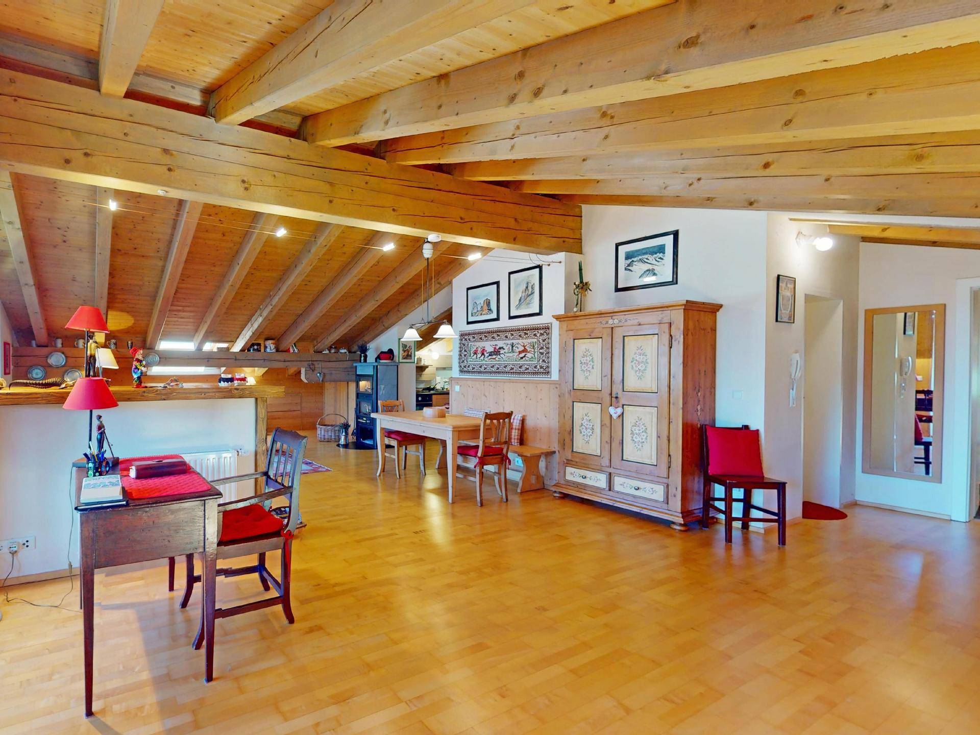 Heller Wohnbereich mit Holzbalken, Parkettboden und traditionellen Möbeln in alpiner Atmosphäre.