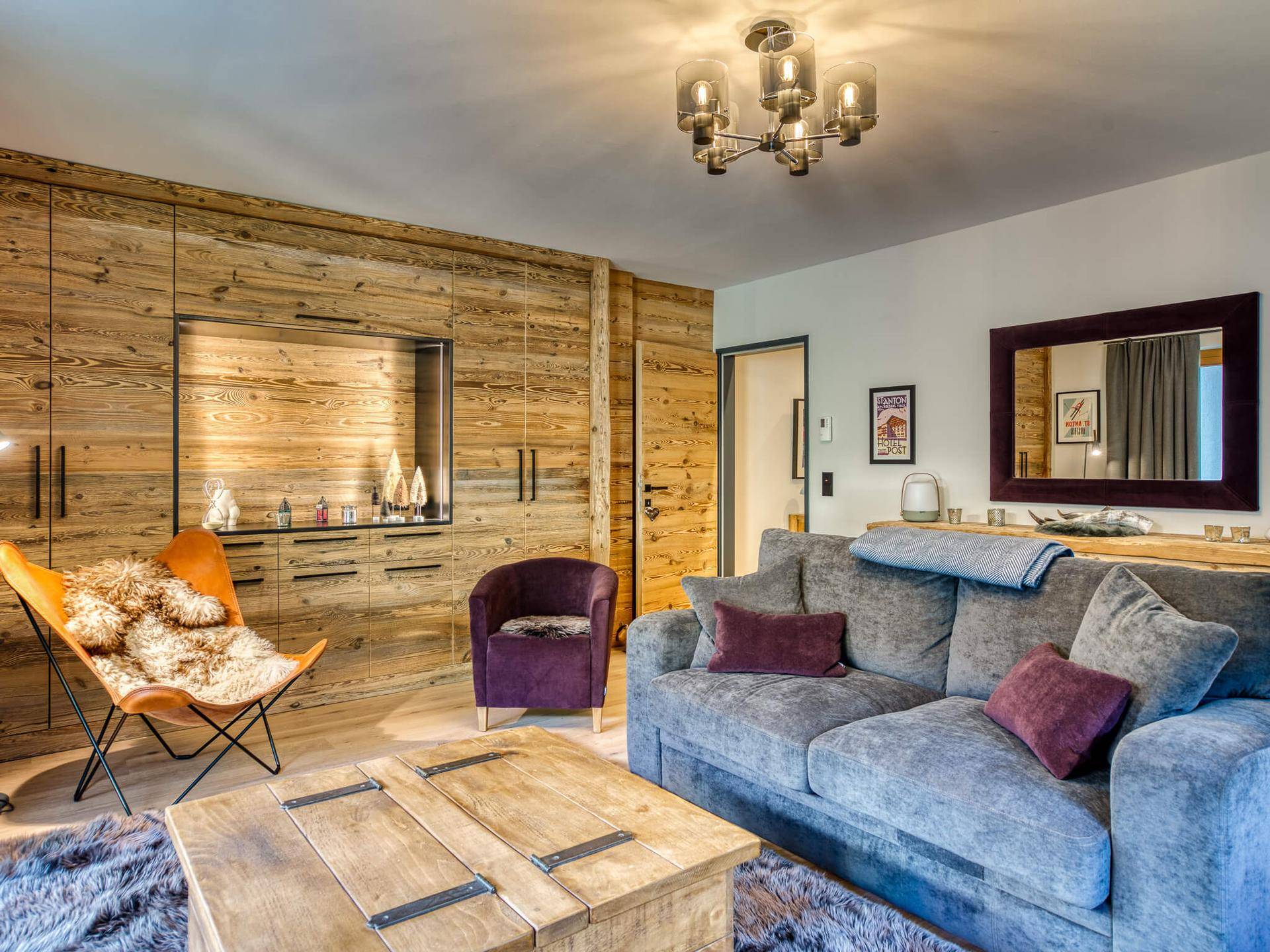 Stilvolles Wohnzimmer mit Holzwandverkleidung, bequemen Sitzmöbeln und moderner Beleuchtung.