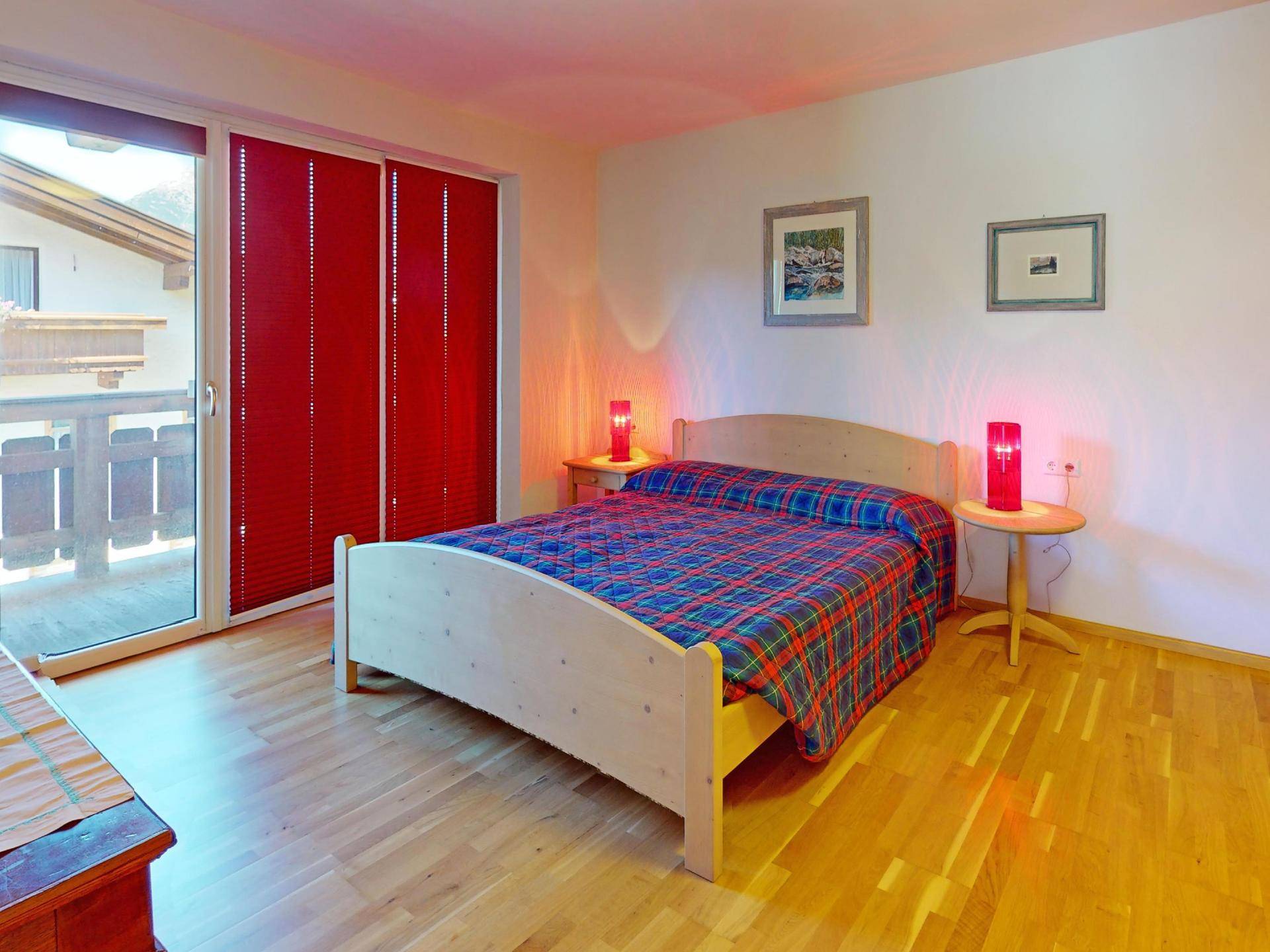 Helles Schlafzimmer mit Holzboden und direktem Zugang zu einem Balkon.