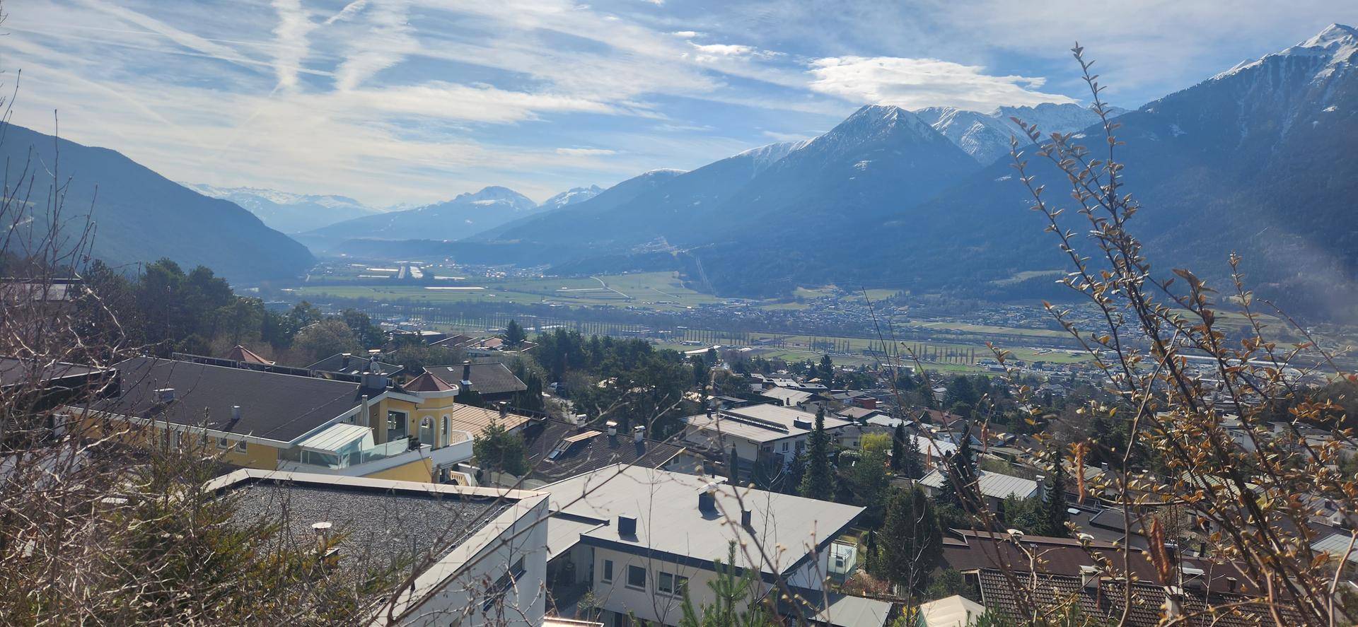 Panoramablick über ein Tal mit einer Stadt und majestätischen Bergen im Hintergrund.