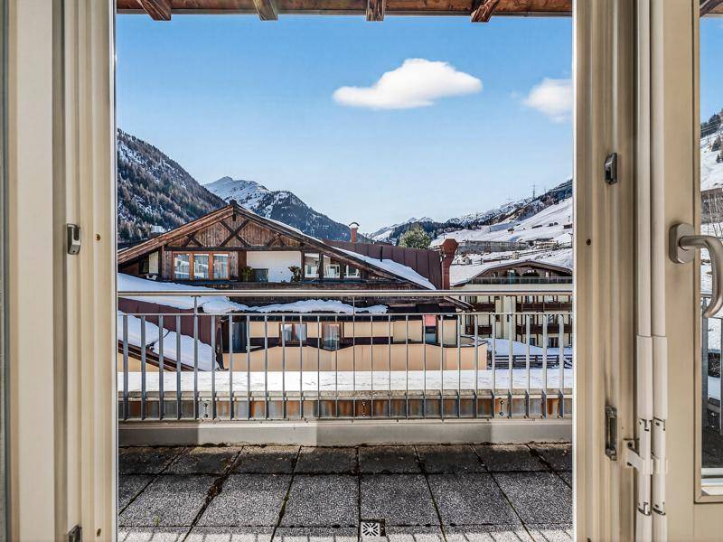 Balkon mit Fliesenboden und Blick auf schneebedeckte Berge und traditionelle Gebäude.