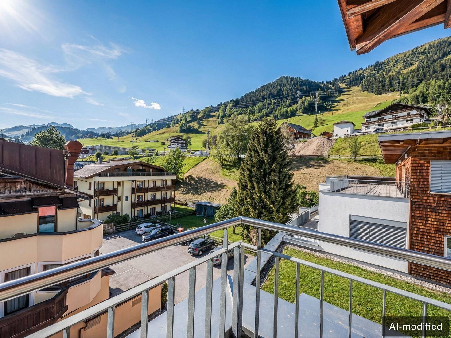 Sonniger Balkon mit Panoramablick auf grüne Hügel, Häuser und die umliegende Berglandschaft.