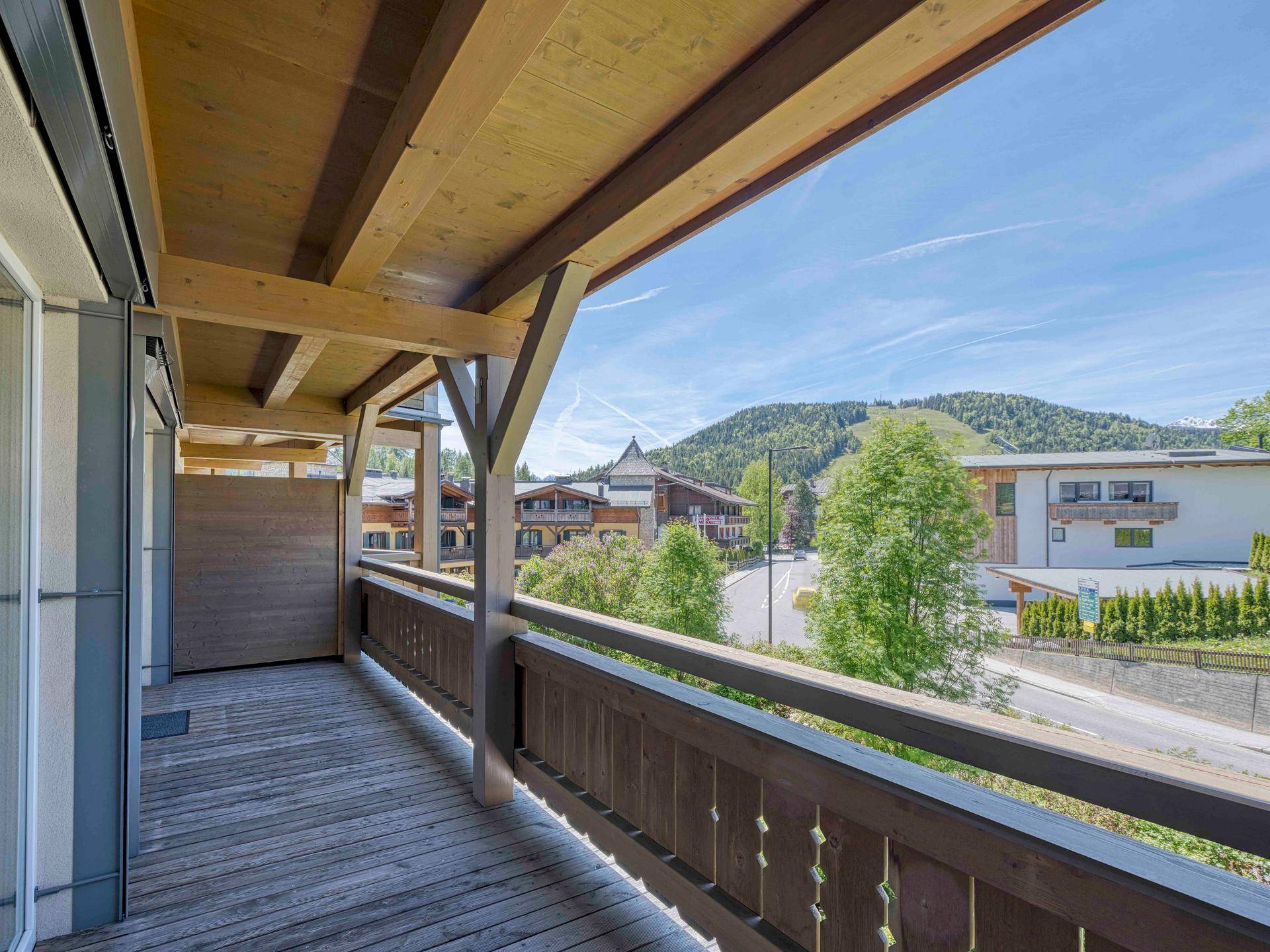 Geräumiger Holzbalkon mit traditionellem Geländer und einem weiten Blick auf die Berge.