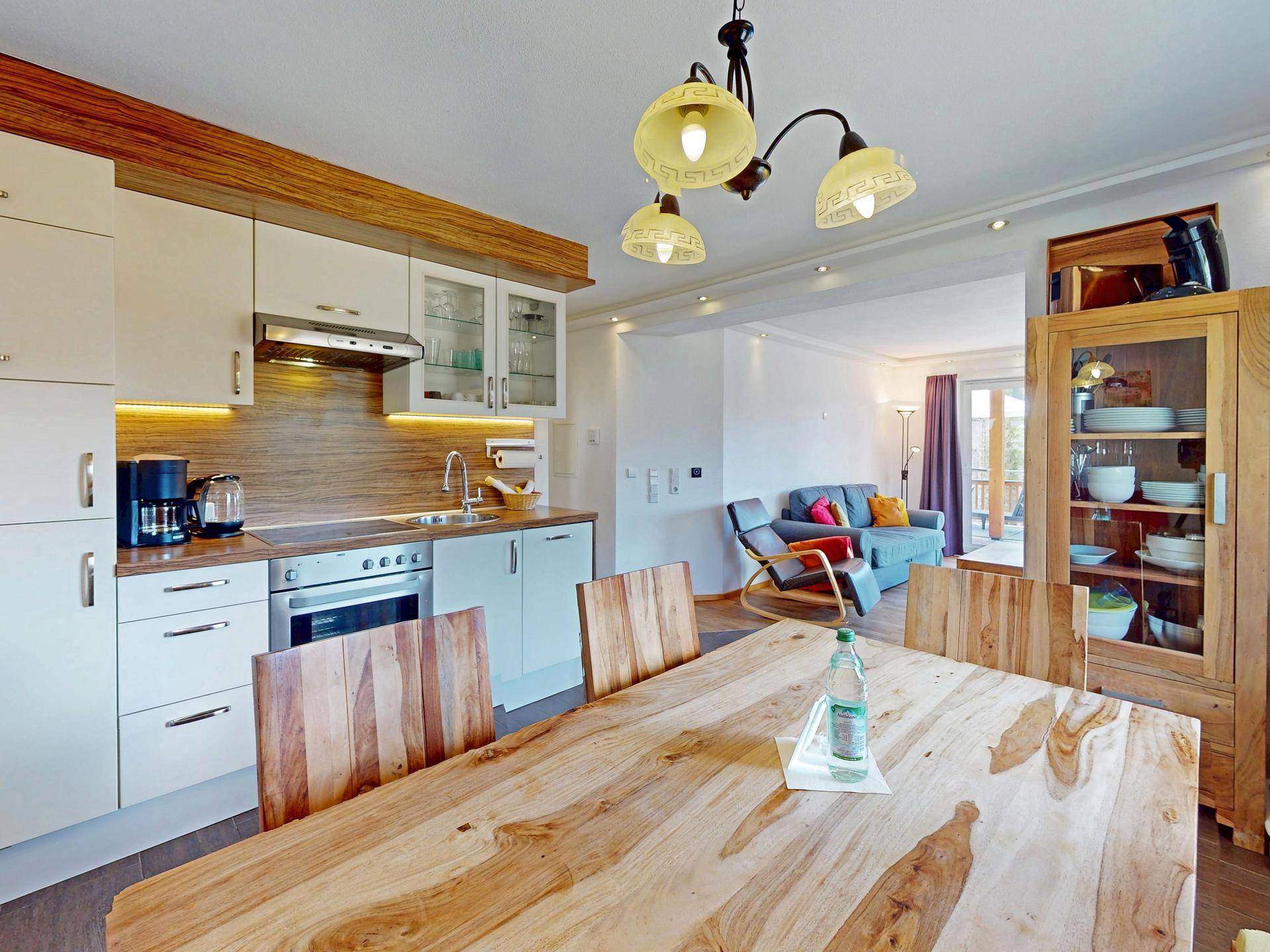 Offene Küche mit Holztisch und modernen Einbauschränken, die in den Wohnbereich übergeht.