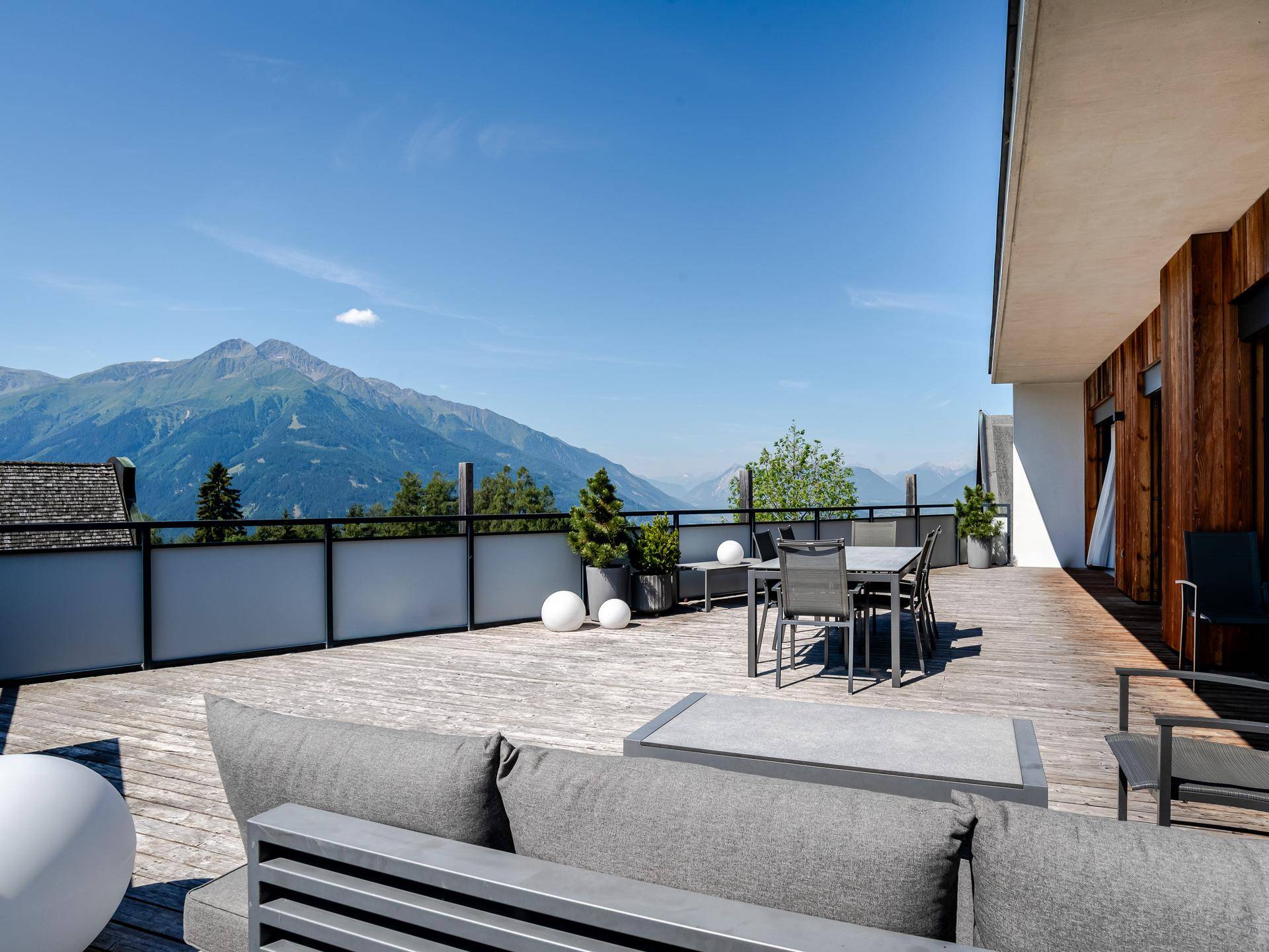 Große Sonnenterrasse mit Sitzgelegenheiten und spektakulärem Panoramablick auf die Berge.