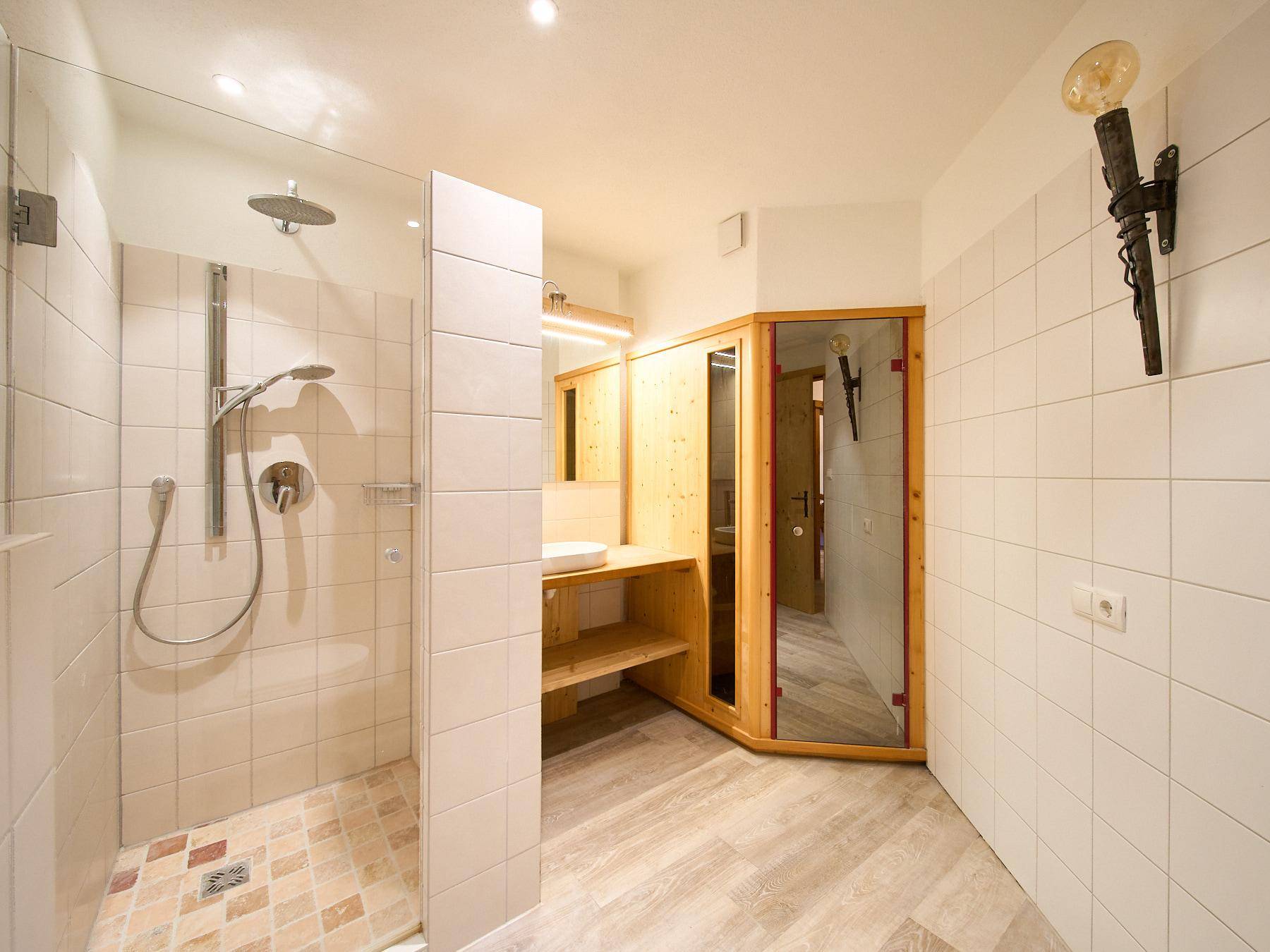 Modernes Badezimmer mit begehbarer Dusche, Fliesen und integrierter Sauna.