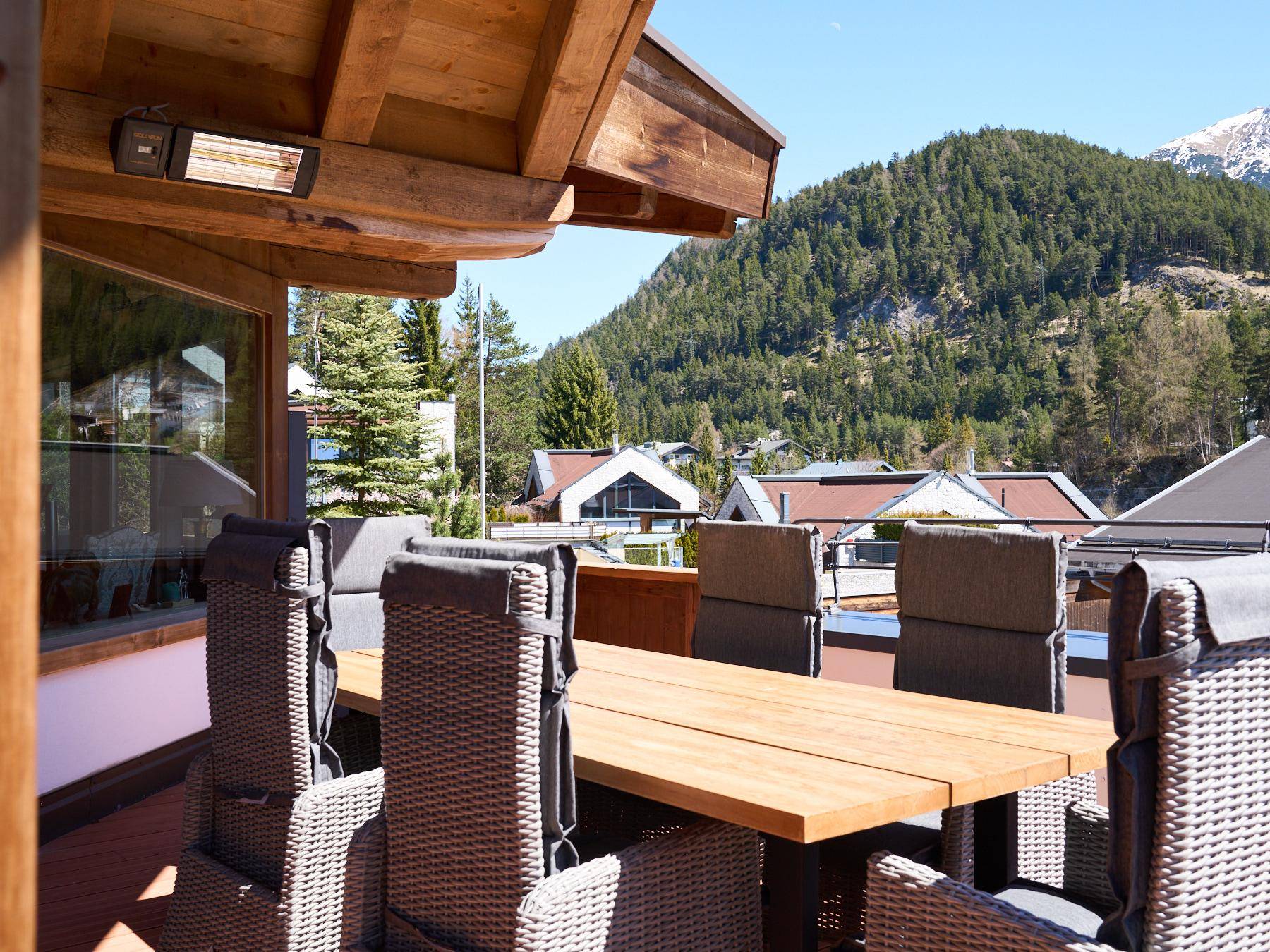 Große Terrasse mit Esstisch, Stühlen und Blick auf die umliegenden Berge und Wälder.