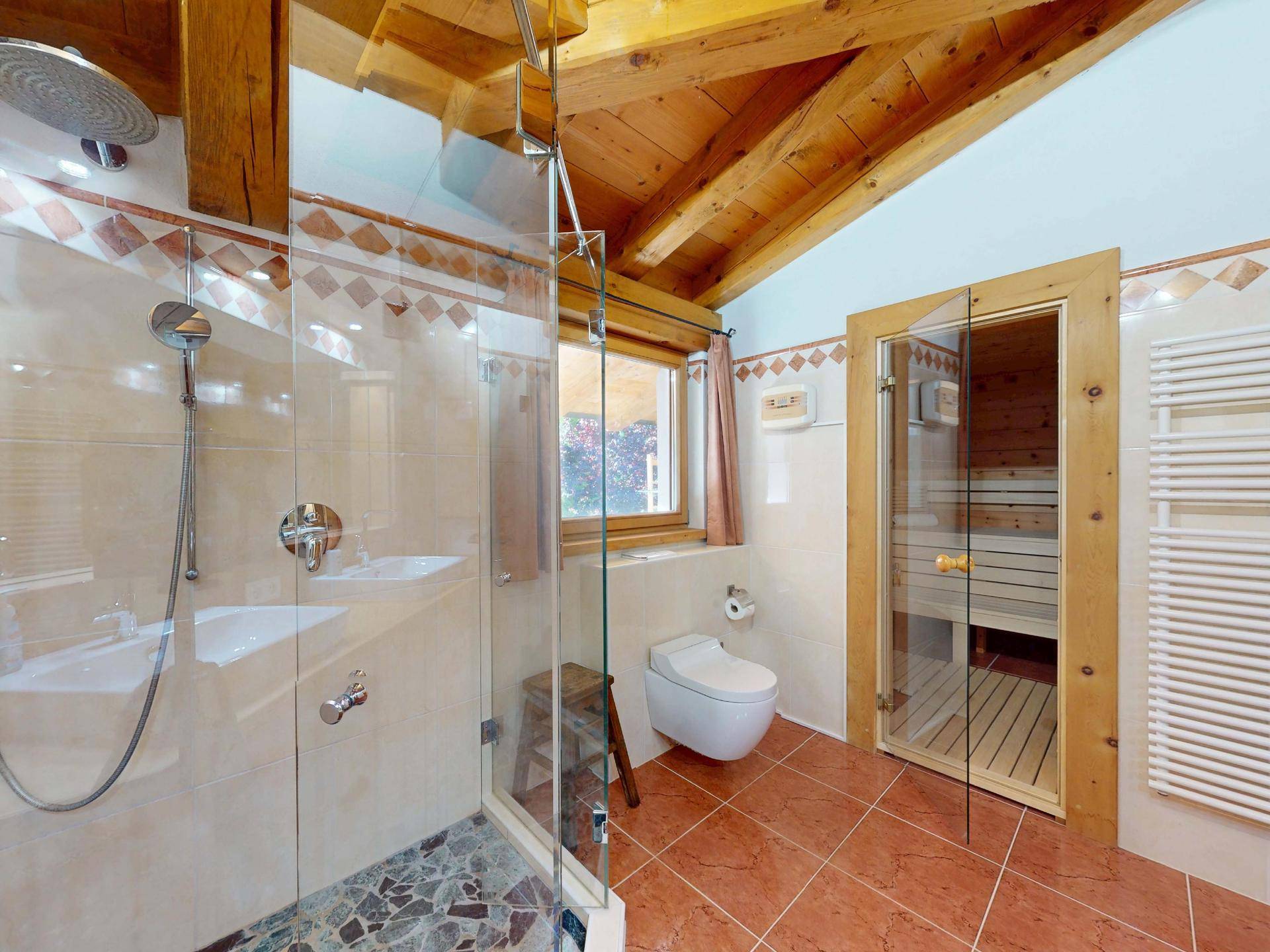 Modernes Badezimmer mit begehbarer Dusche, WC, Handtuchheizkörper und integrierter Sauna.