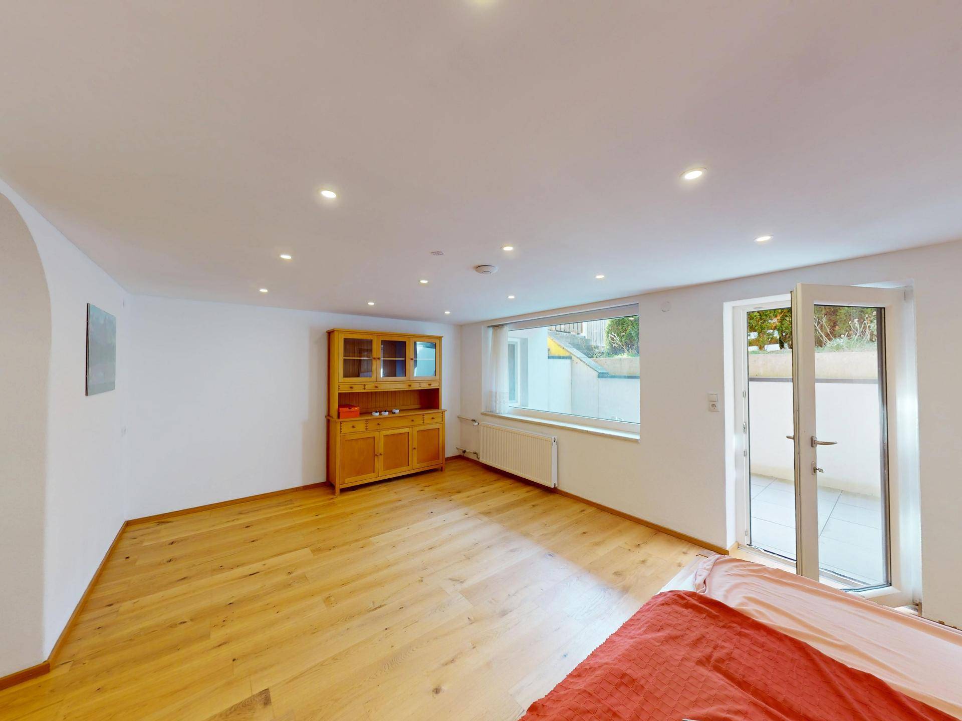 Geräumiges Schlafzimmer mit Holzboden, Einbaustrahlern und Zugang zu einem Außenbereich.