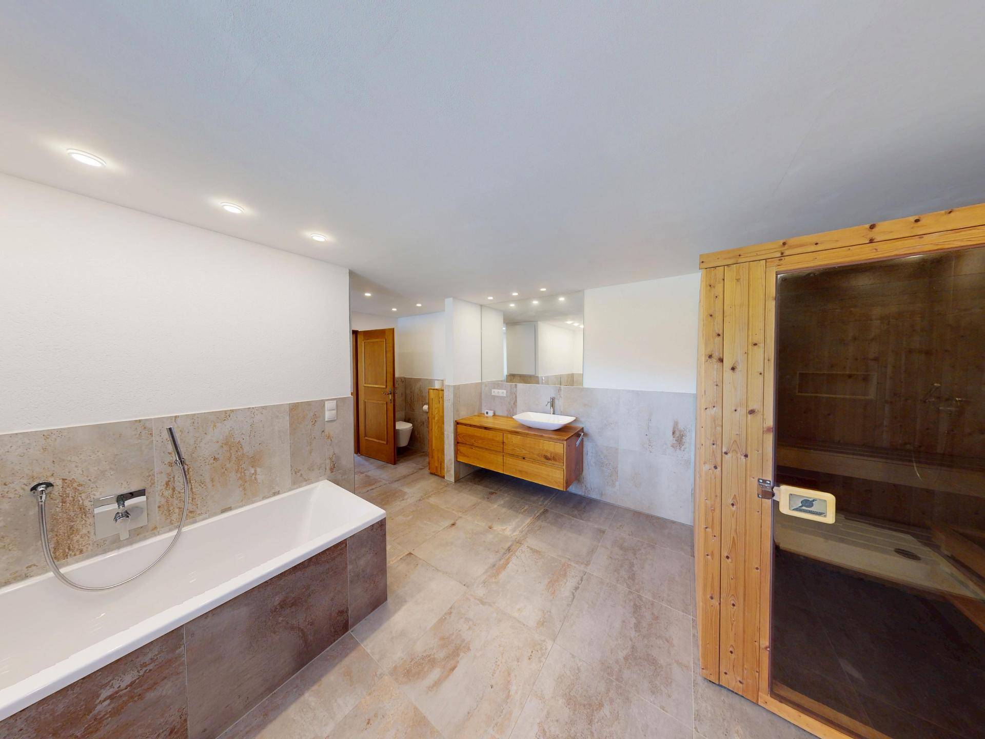 Geräumiges Badezimmer mit Badewanne, modernem Waschtisch und integrierter Sauna.