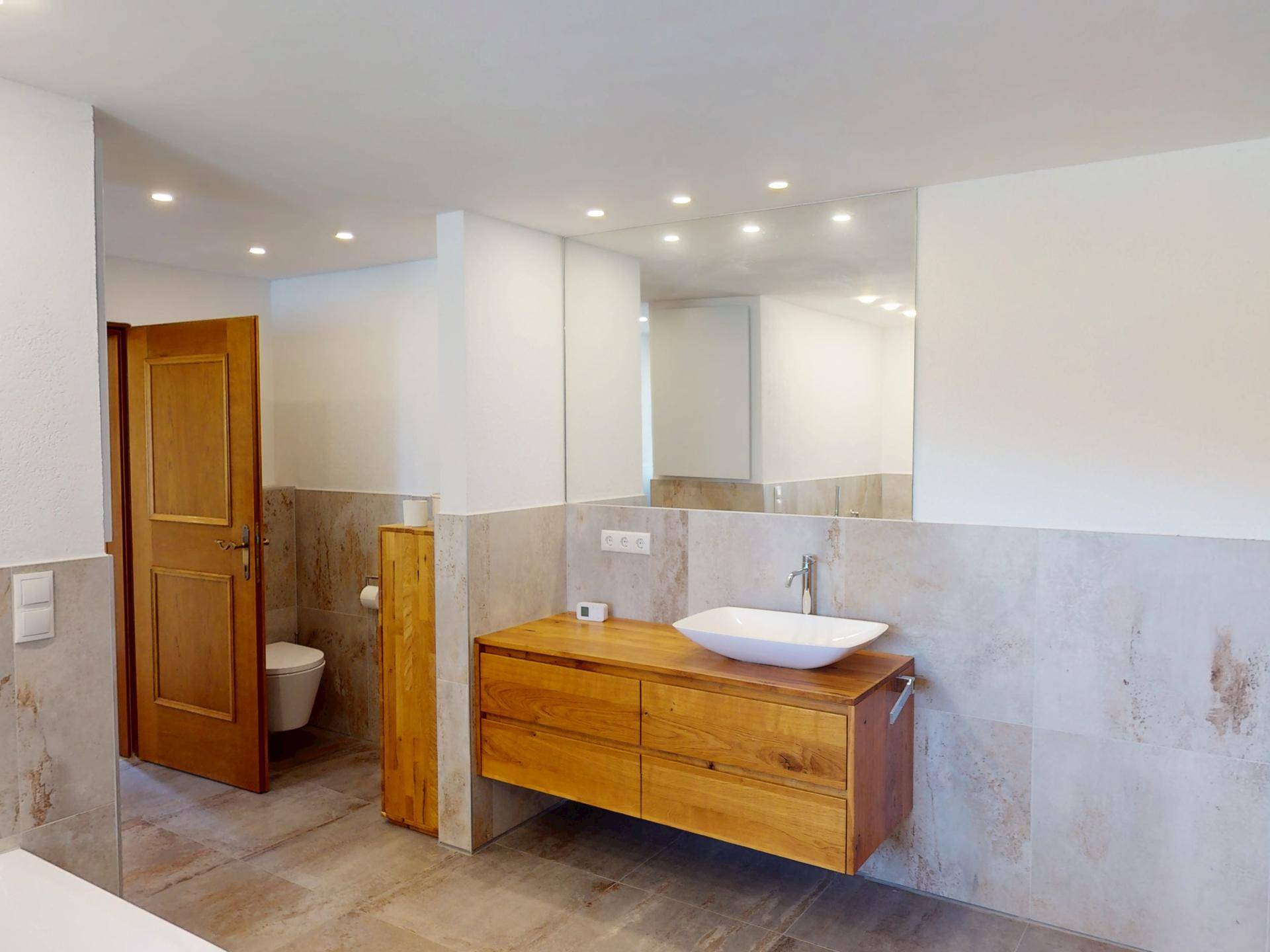 Modernes Badezimmer mit schwebendem Holzwaschtisch, Aufsatzwaschbecken und großen Spiegeln.
