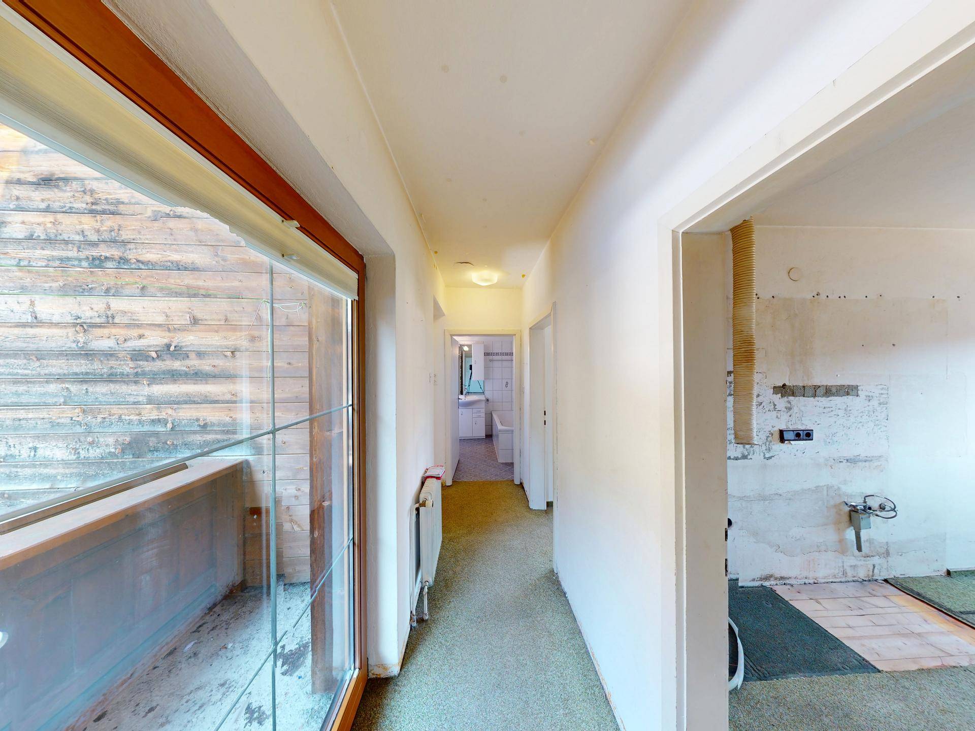 Heller Flur mit Teppichboden, großem Fenster und Zugang zu weiteren Räumen im Haus.