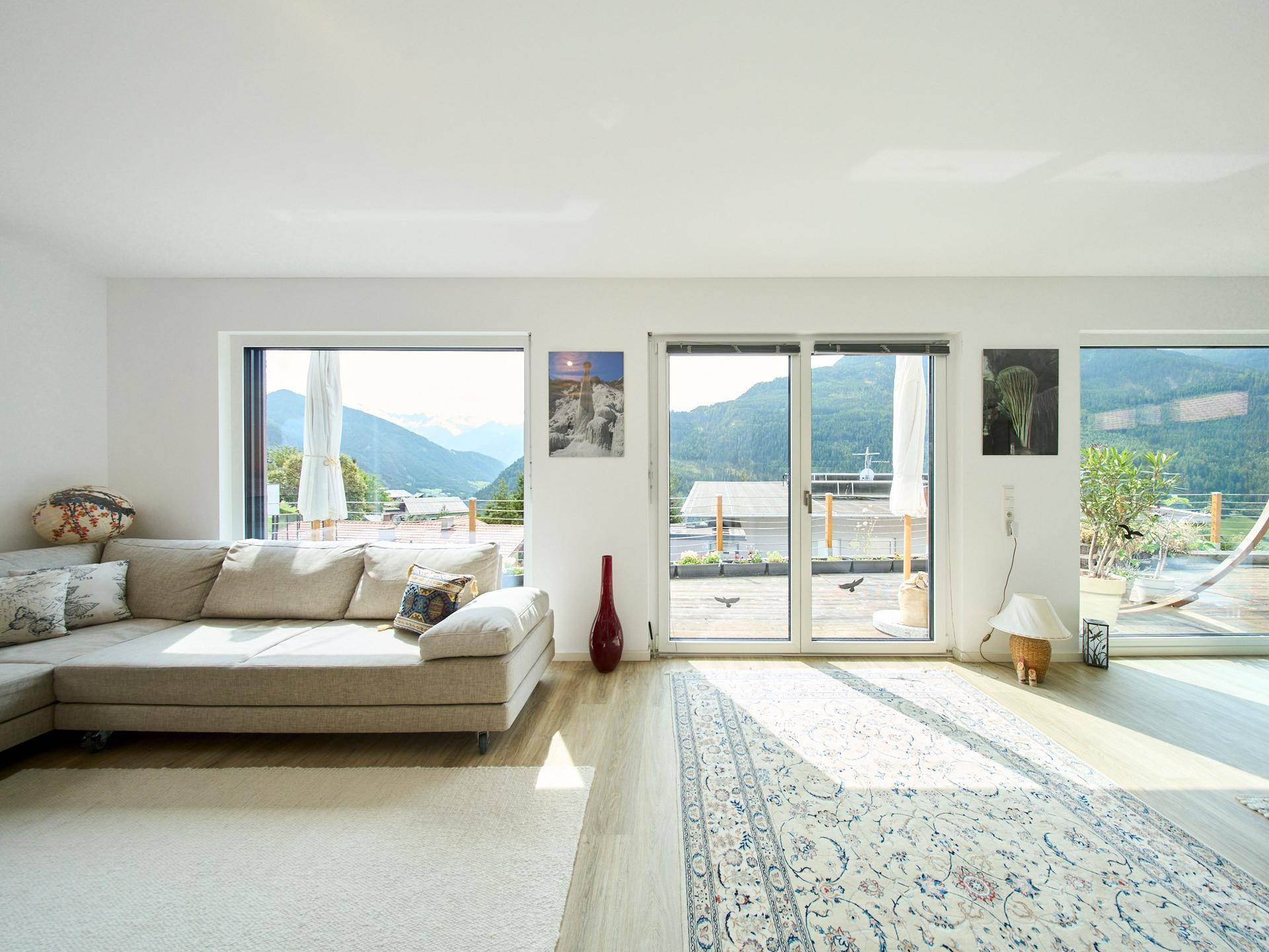 Lichtdurchflutetes Wohnzimmer mit beigem Sofa und weitem Blick auf die Berge.